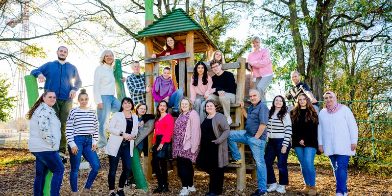 Eine Gruppe Frauen und Männer steht draußen vor einem Spielgerät.