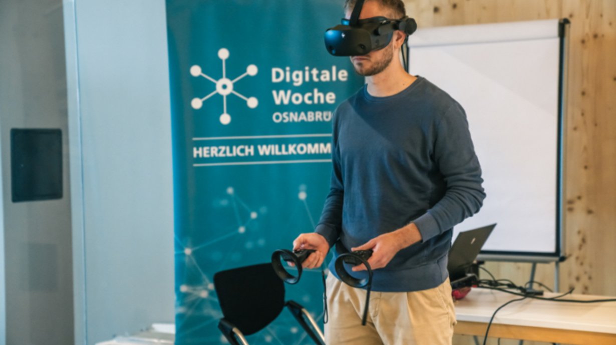 Person mit VR-Brille vor Roll up der Digitalen Woche.