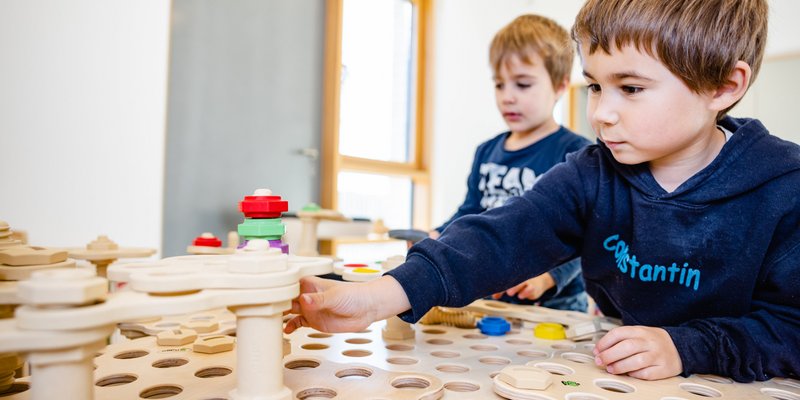Zwei Jungs spielen mit Holzspielzeug.