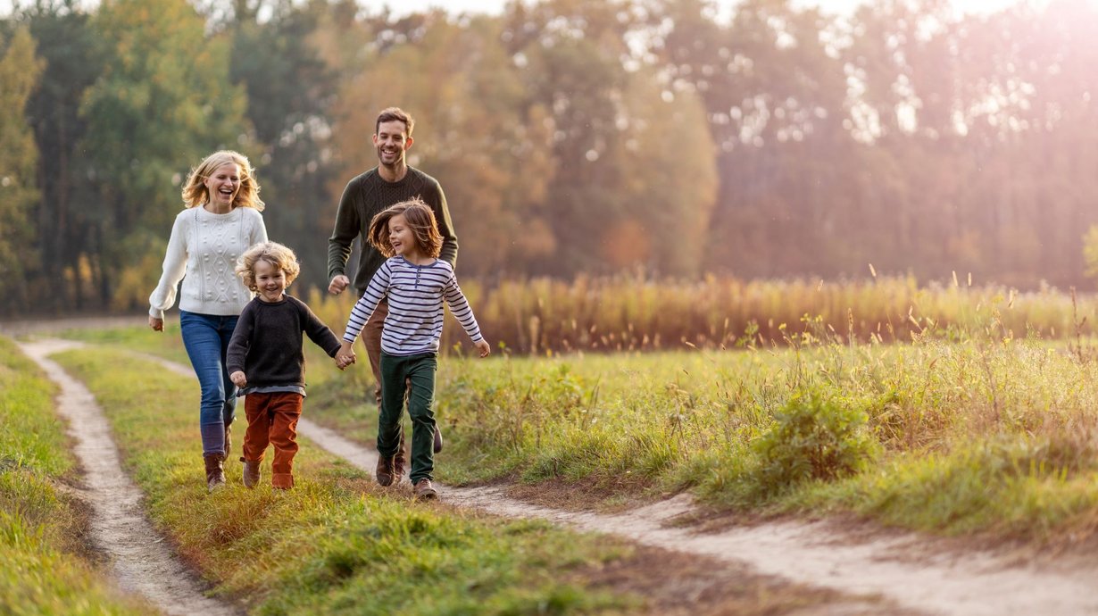 Mutter, Vater und ihre beiden Söhne laufen über einen Feldweg